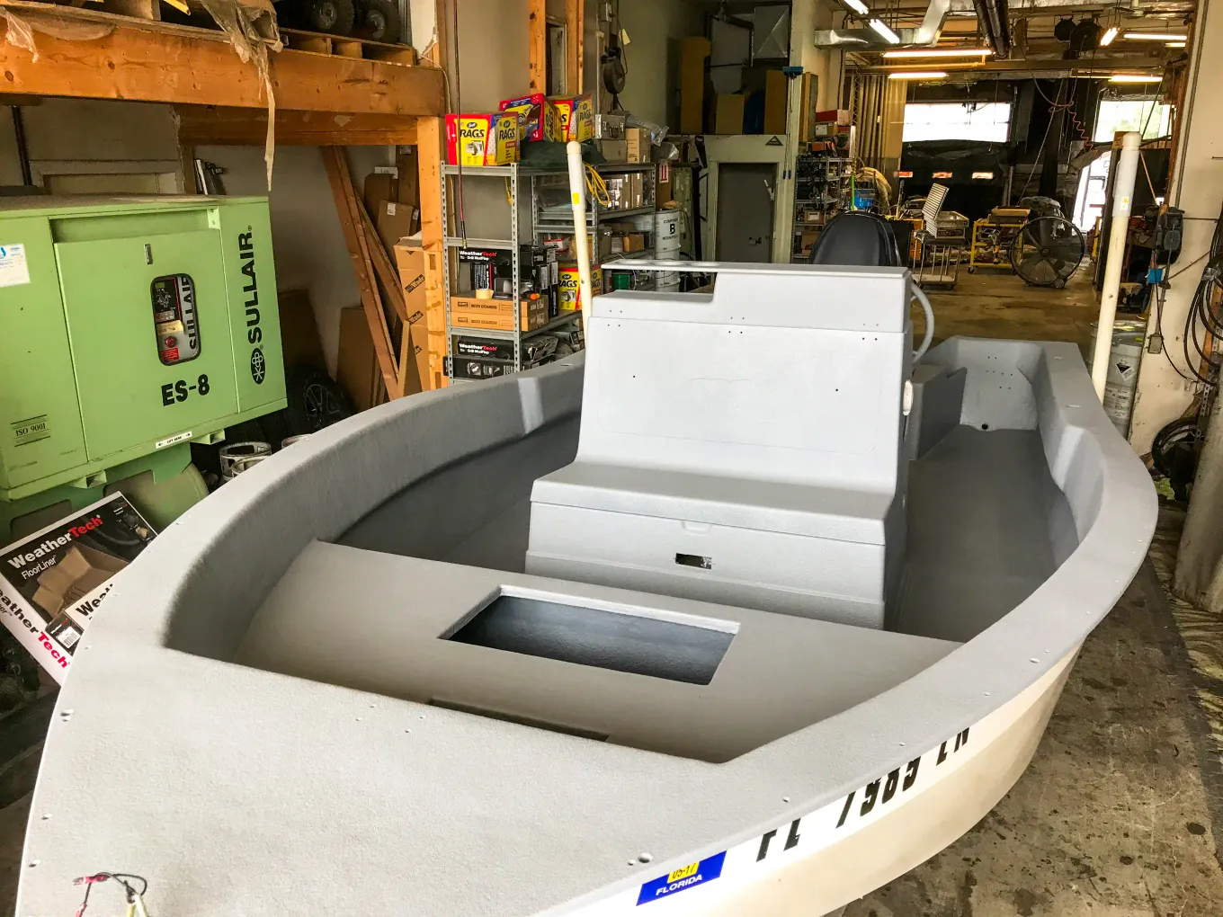 Boat interior coated in gray protective coating inside the shop
