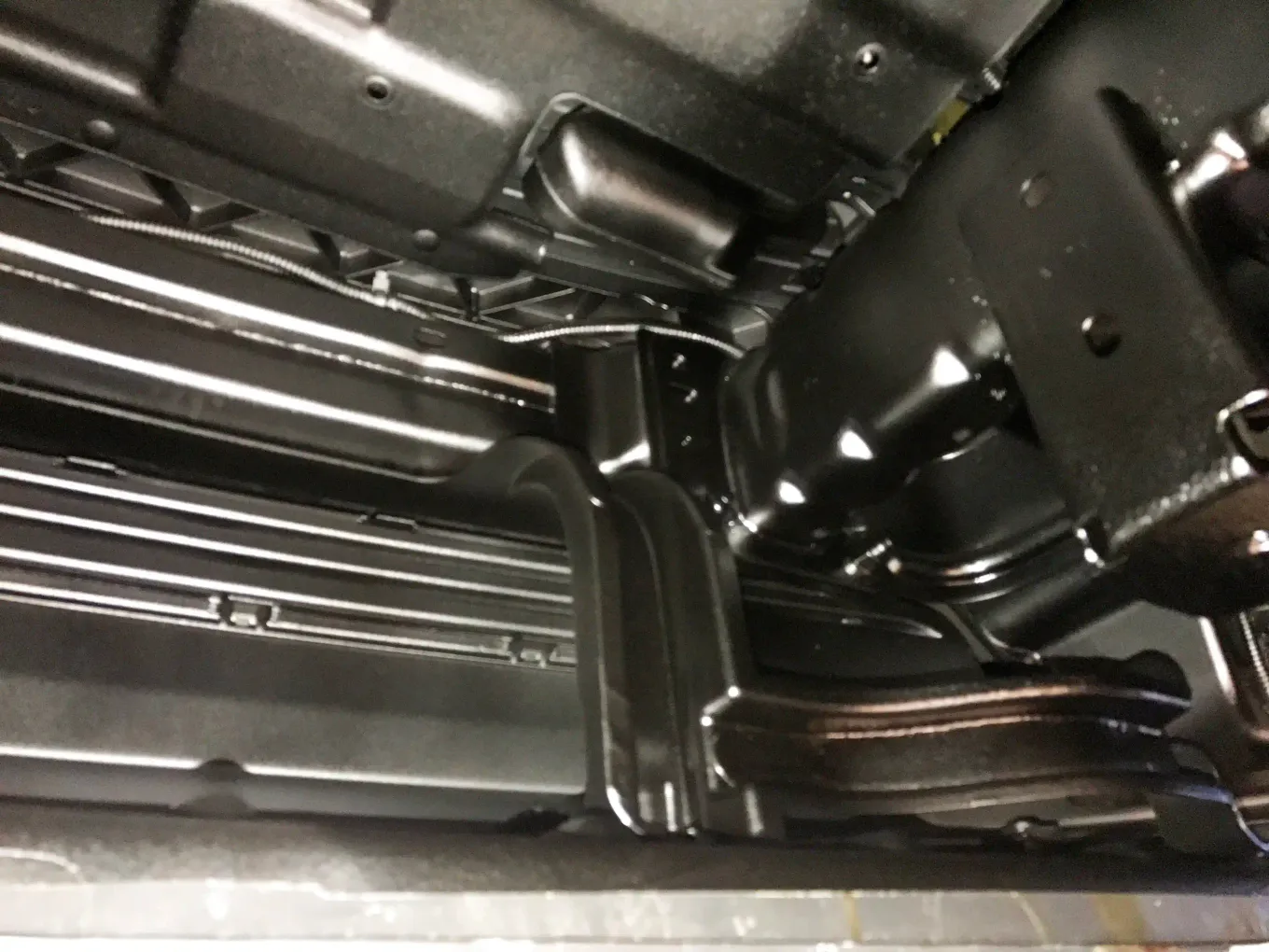 Close-up of glossy black rustproofing coverage on underbody frame and rocker seams